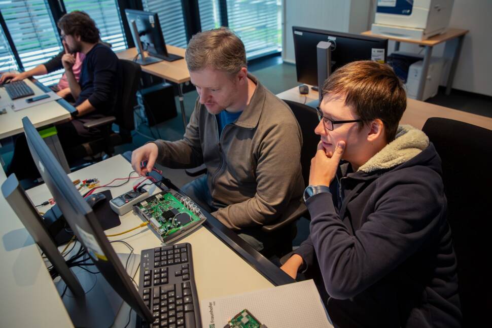Zwei Männer schauen auf einen Rechner: Blick ins Ausbildungslabor.