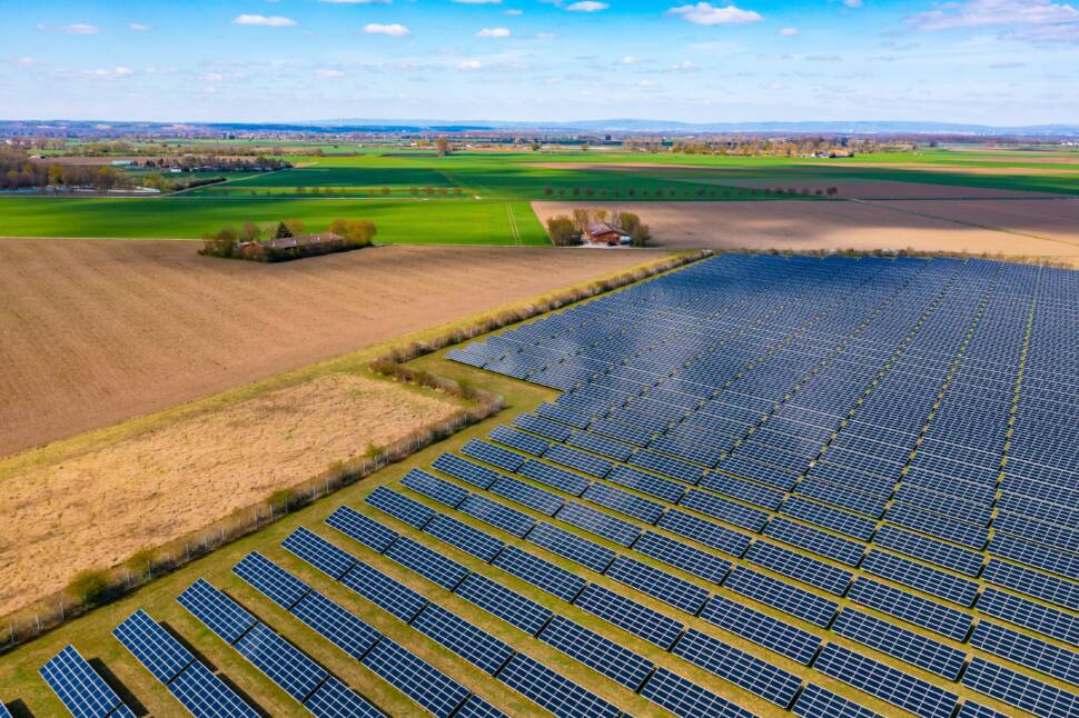 Aerial view of a solar park with many photovoltaic panels next to agricultural fields in rural Germany