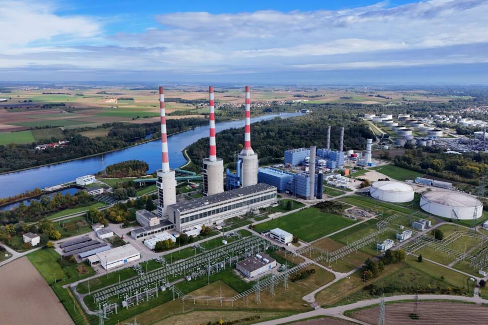 Großes Kraftwerk mit drei rot-weißen Schornsteinen an einem Fluß - Luftaufnahme