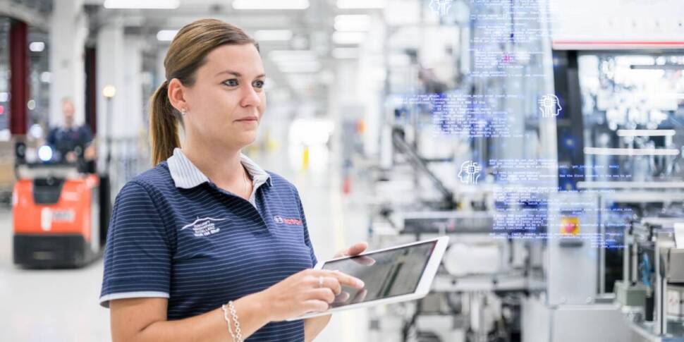 Frau mit Tablet-Computer in einer Fertigungshalle