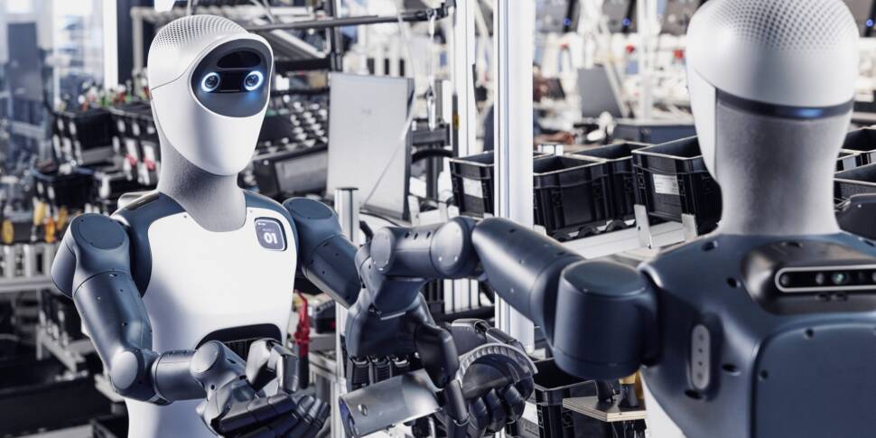 Zwei humonoide Roboter übergeben einander ein Bauteil