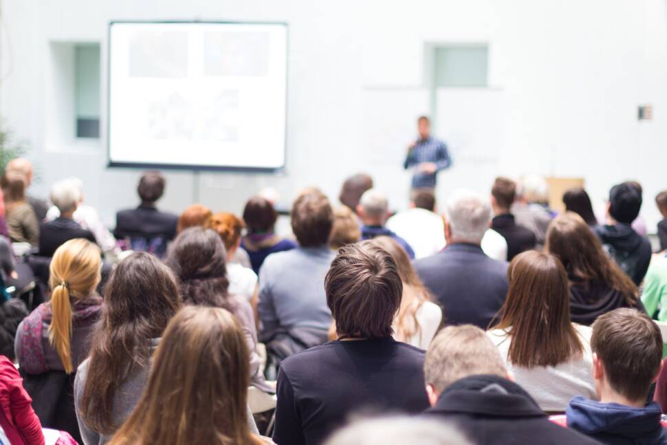 Hörsaal mit Studierenden und vorne ein Dozent