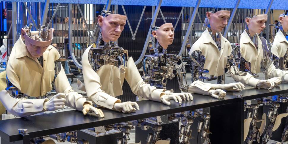 Mehrere humanoide Roboter mit menschlichen Gesichtern an einem großen Tisch
