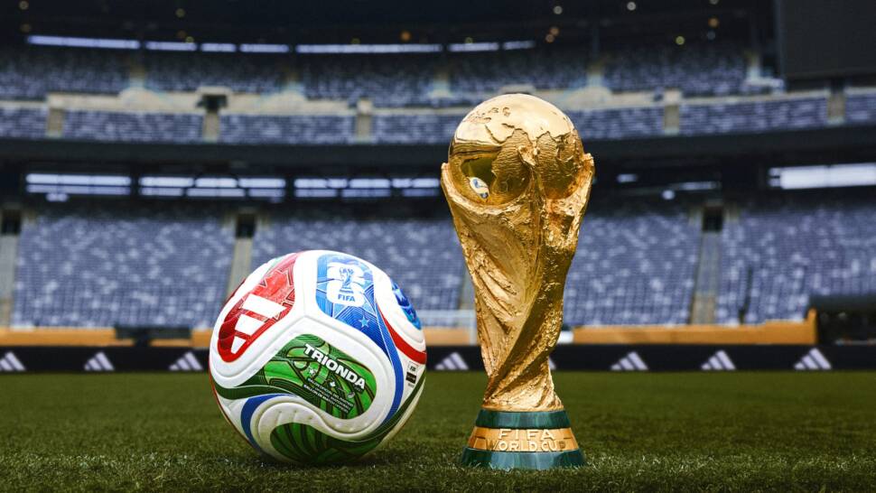 Offizieller Ball zur Fußball-WM 2026 daneben der Weltmeister-Pokal im Hintergrund eine Fußballstadion