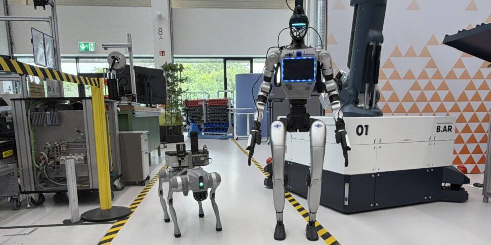 Ein humanoider Roboter mit integriertem Brust-Radar und ein vierbeiniger Laufroboter befinden sich in der Forschungsfabrik ARENA2036 in Stuttgart. Im Hintergrund stehen Industrieanlagen und Robotersysteme.
