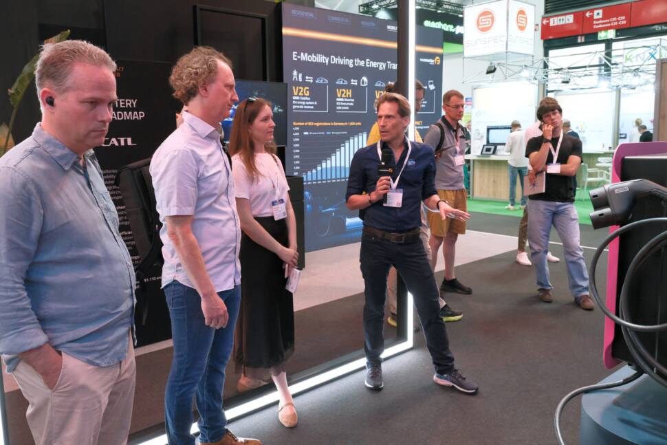 Messe Power2Drive - drei Menschen lassen sich auf einem Messestand ein Exponat zur Elektromobilität erklären