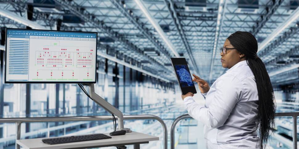 Mitarbeiterin in Fabrikhalle nutzt Tabelt-Computer mit KI