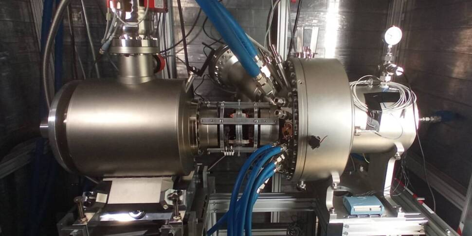 Man sieht eine große silberne Metallröhre mit blauen Schläuchen an den Seiten.