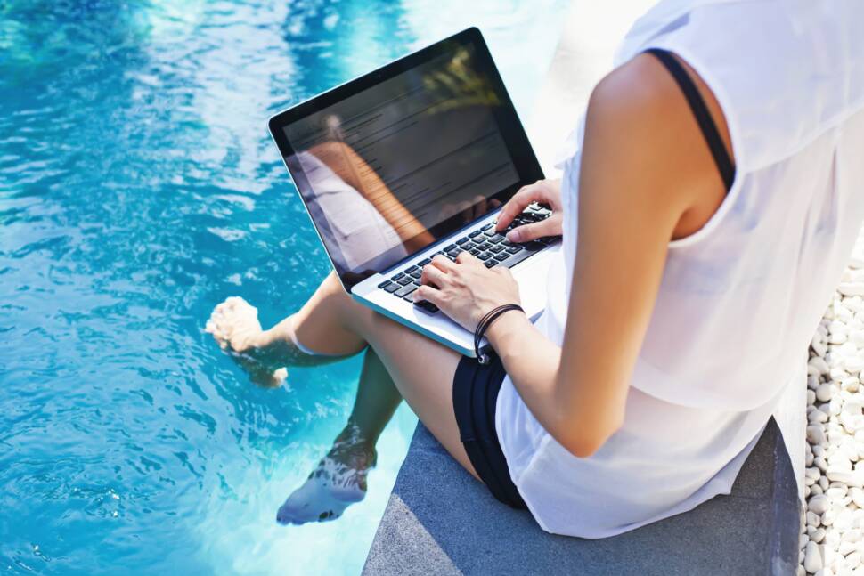 Frau arbeitet am Laptop am Pool