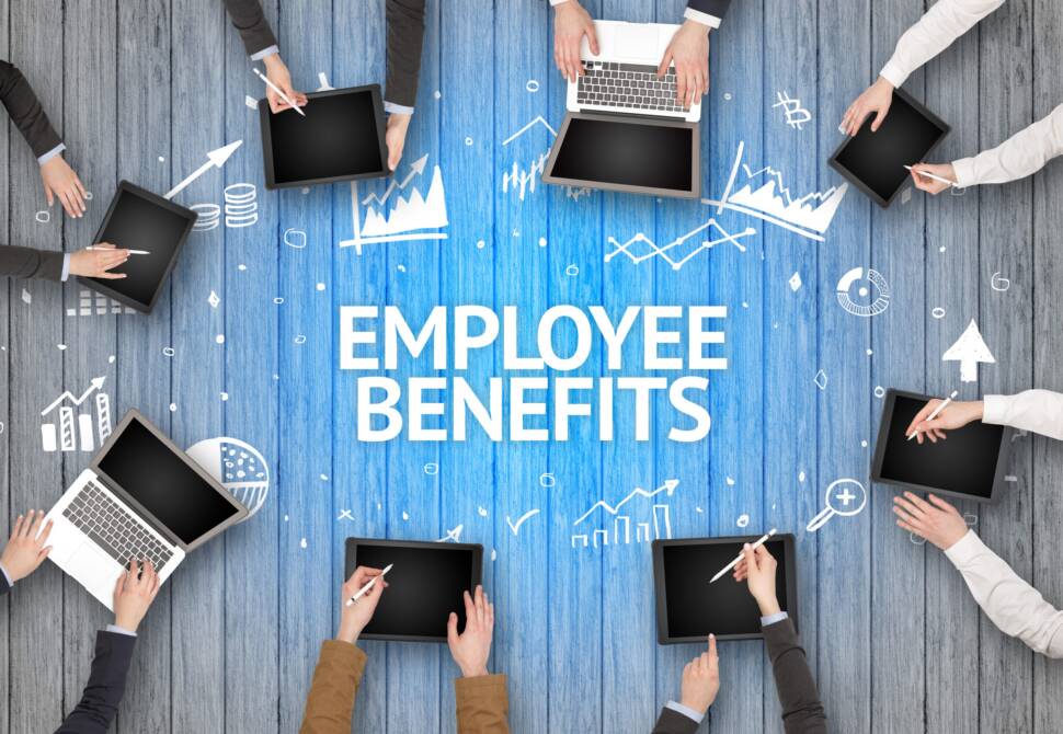 Gruppe sitzt am Tisch, auf dem Employee Benefits steht.