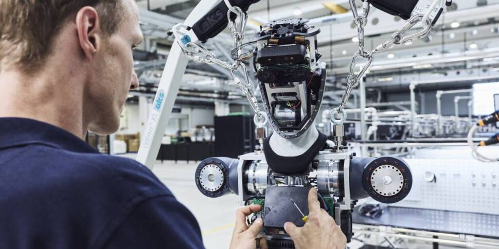Ein Mensch montiert den Oberkörper eines humanoiden Roboters.