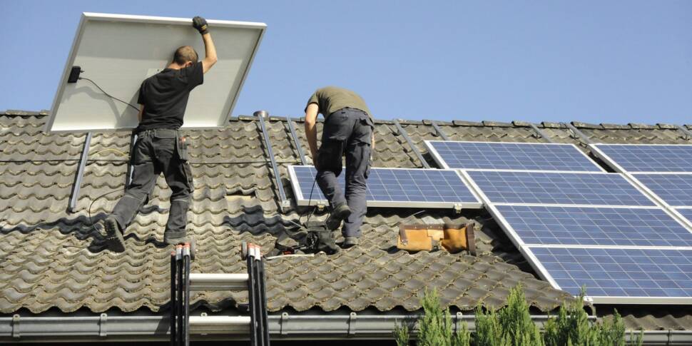 Zwei Männer installieren Photovoltaikpaneele auf einem Dach