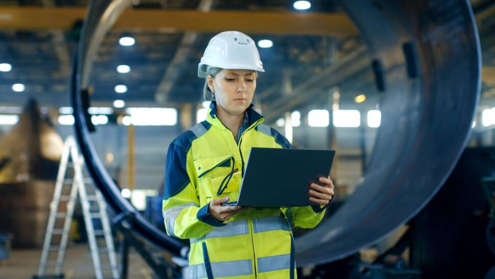 Frau mit Helm schaut auf Laptop